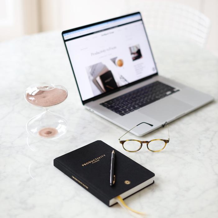 An Intelligent Change productivity planner and a glass of wine on a white table.