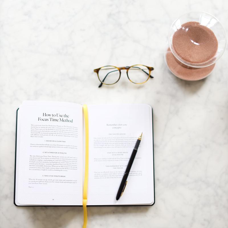An Intelligent Change Productivity Planner and a cup of coffee on a marble table.