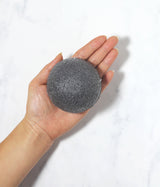 A person holding a Florence KONJAC PREMIUM FACIAL PUFF SPONGE WITH BAMBOO CHARCOAL in their hand.