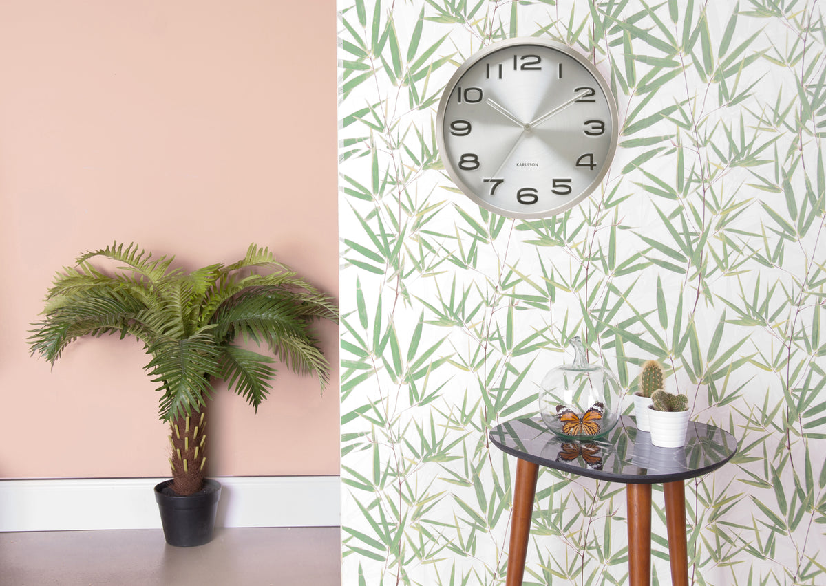 Maxie wall clock styled on leafy wallpaper above a small side table