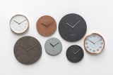 A group of different colored Karlsson Slate Clock Black - Mediums on a white wall.