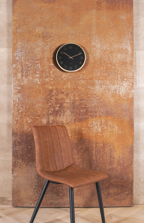A brown leather chair in front of a Karlsson wall clock and Gold Elegance - White / Black on a rusty wall.