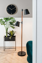 An aesthetically minimal black floor lamp complements the design of a Dots & Batons Wall Clock - Various Colours by Karlsson, alongside a plant.