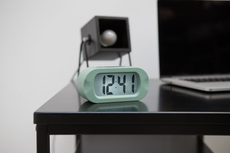 A Karlsson digital clock, known for its Scandinavian design, sits on a desk.
