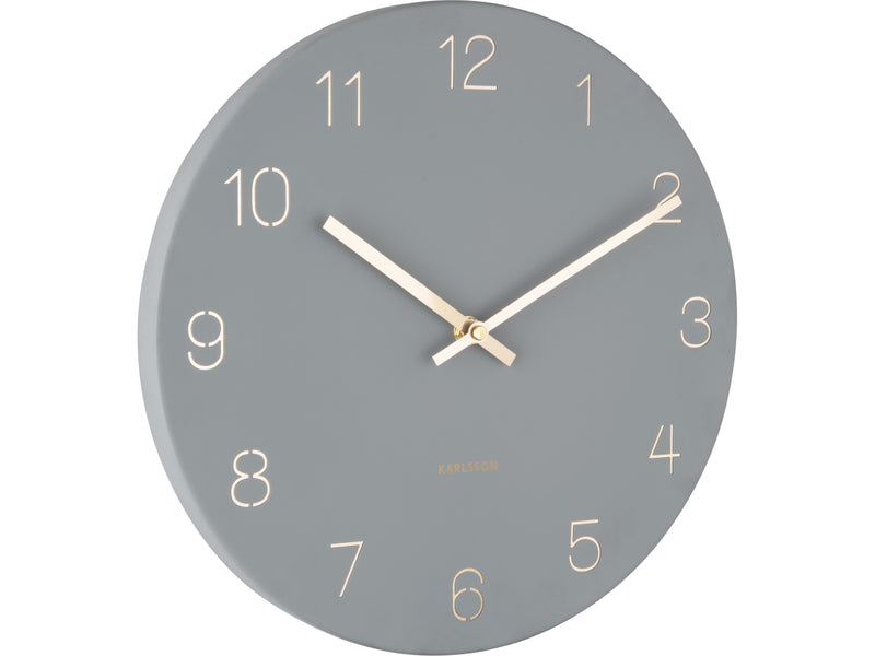 A Karlsson Charm Wall Clock - Various Colours with engraved gold numbers on a grey background.