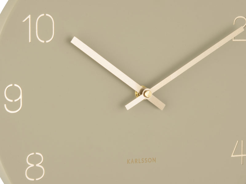 A Karlsson Charm Wall Clock with engraved gold numbers on a beige background.