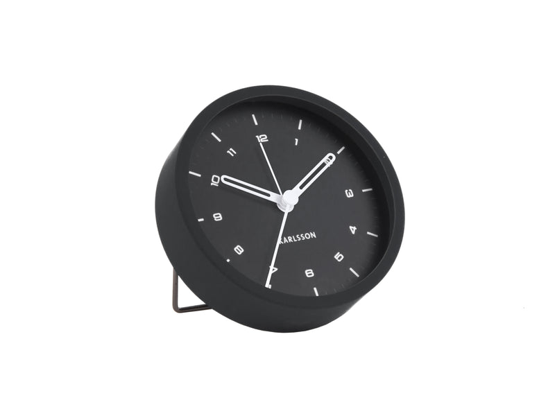 A small foldable foot silent Tinge Alarm Clock - Black by Karlsson sitting on a white surface.