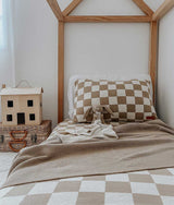 A bed in a room with a CLASSIC KNIT BLANKET - KHAKI by Bengali Collections.