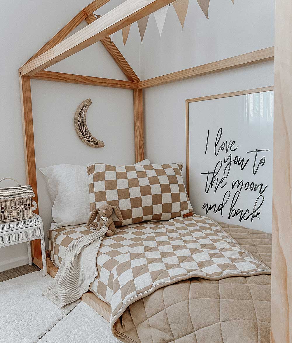 House frame bed with the khaki gingham check pillowcase, a khaki quilt and a moon wall hanging
