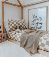 A child's room with a checkered bed and a Bengali Collections CLASSIC KNIT BLANKET - KHAKI.