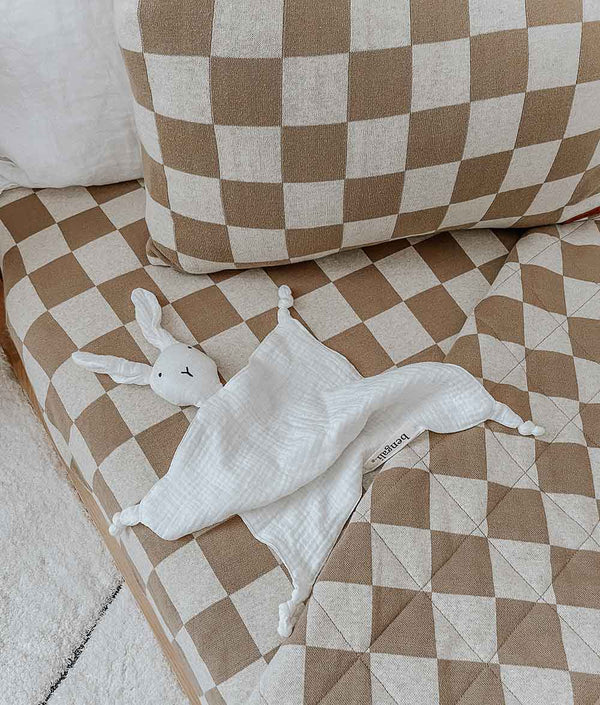 A white and brown checkered JERSEY SHEET - KHAKI GINGHAM blanket on a bed by Bengali Collections.