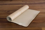 A roll of Yogatribe | Organic Jute 100% Eco Yoga Mats - Various Options on a wooden floor.