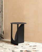 A modern Made of Tomorrow Arch Side Table ∙ Black in front of a tiled floor, serving as a durable display table.
