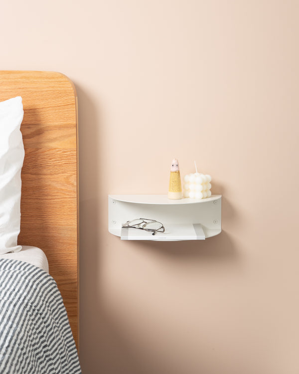 A bed with a shelf and the FOLD Bedside Table Mini ∙ White, designed for smaller spaces or limited space, made by Made of Tomorrow.
