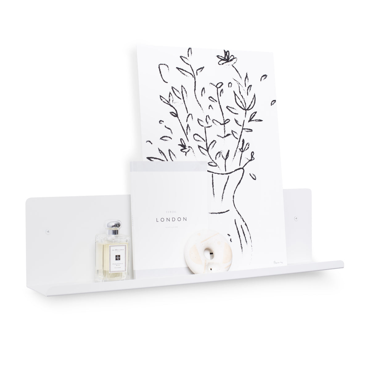 A FOLD Display Ledge 600mm ∙ White wall shelf with flowers and a bottle of Made of Tomorrow perfume providing display space.