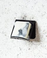 A FOLD Soap Block Holder ∙ Black on a concrete wall, made by Made of Tomorrow.