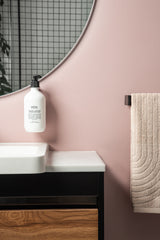 A bathroom with pink walls and a Made of Tomorrow FOLD Bottle Holder ∙ White mirror.