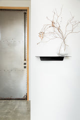 A functional shelf with a vase on the Made of Tomorrow FOLD Ledge 450mm ∙ White next to a door.