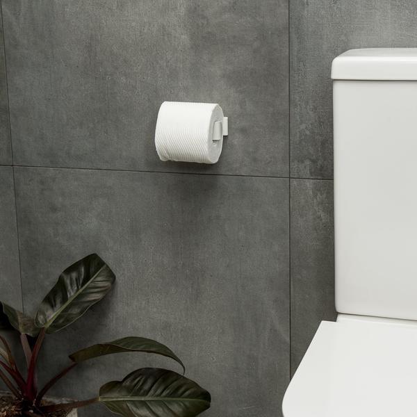 A Made of Tomorrow FOLD Toilet Roll Holder ∙ White in a bathroom with a plant in the background.