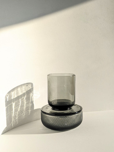 An ALLIRA ORGANIZER - SMOKE by Umbra sits on top of a white table as a stylish centerpiece.
