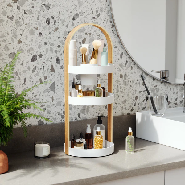 An Umbra BELLWOOD Cosmetic Organizer with three tiers of shelves and a mirror, perfect for showcasing cosmetics and organizing makeup brushes.