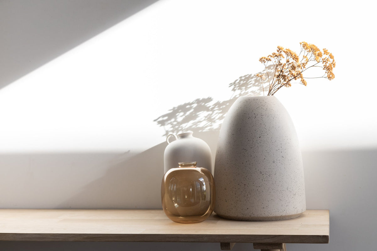 A wooden table with two Harmie Vases - Various Options by Ned Collections on it.