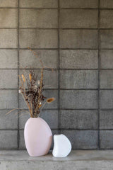 Two Harmie vases by Ned Collections on a table next to a concrete wall.