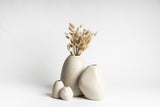 Three white vases with dried grass in them, hand-crafted by Vietnamese Artisans for a unique and Ned Collections' HARMIE Pebble Vase - Natural.