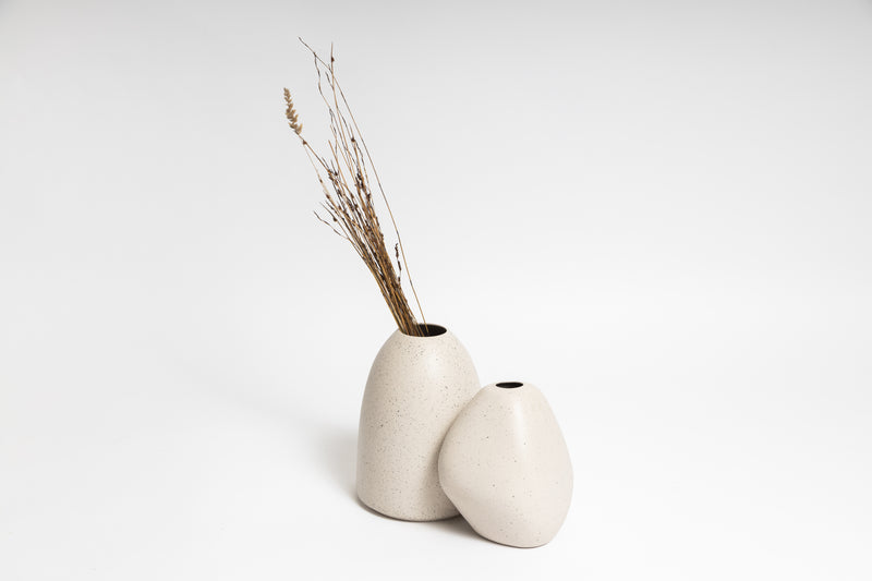 Two HARMIE Pebble Vases, hand-crafted by Vietnamese artisans, adorned with dried grass on a white surface, created by Ned Collections.