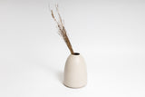 A HARMIE Pebble Vase - Natural, hand-crafted by Vietnamese Artisans, with a bunch of dry grass in it, exuding a rustic and artistic feel.