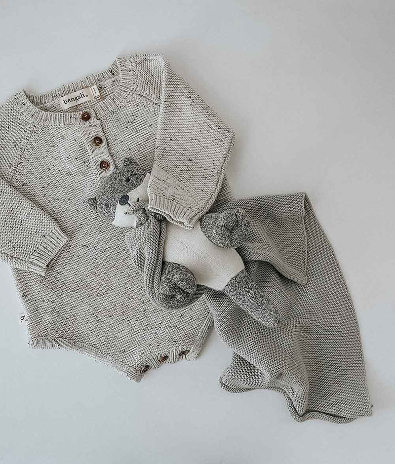 A grey SEA OTTER SNUGGLY sweater made with Oeko-tex Certified Cotton yarns and accompanied by a teddy bear from Bengali Collections.