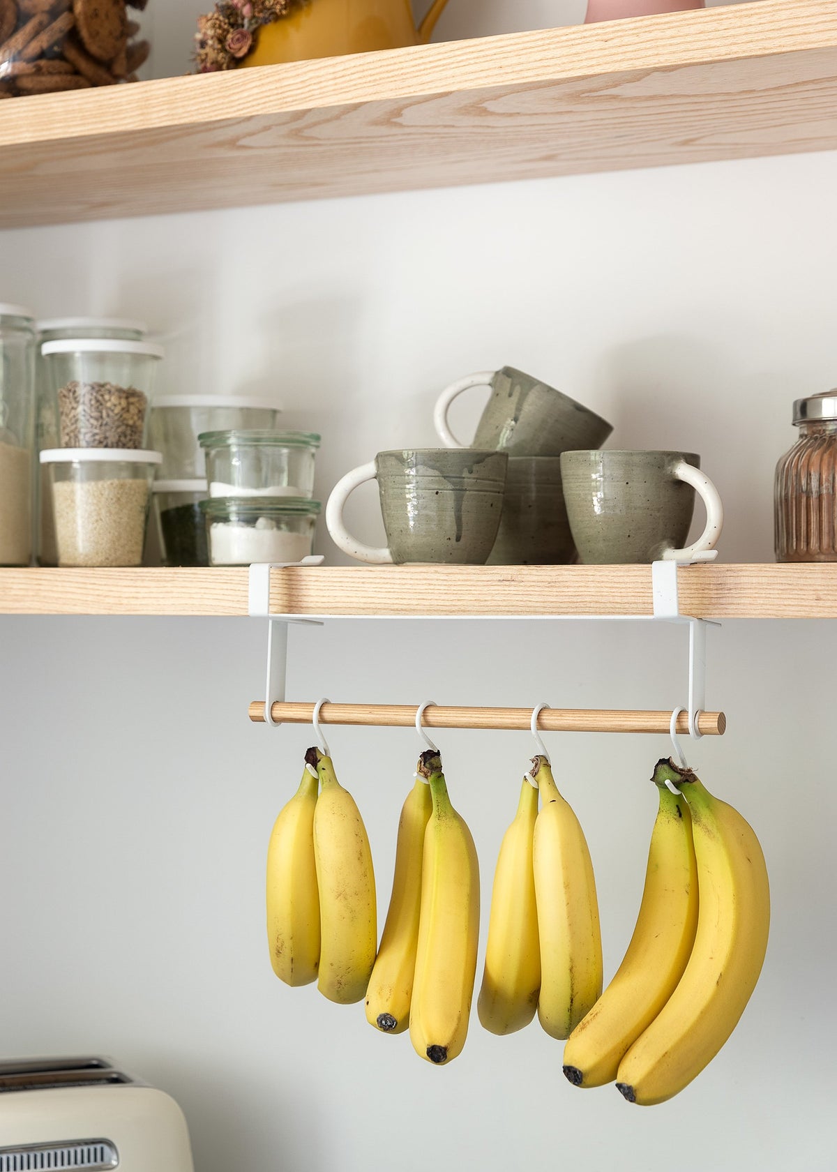 Books hanging from a shelf in a kitchen.
