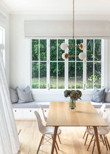 A white dining room with a wooden table and chairs, Our Spaces - Contemporary New Zealand Interiors brand.
