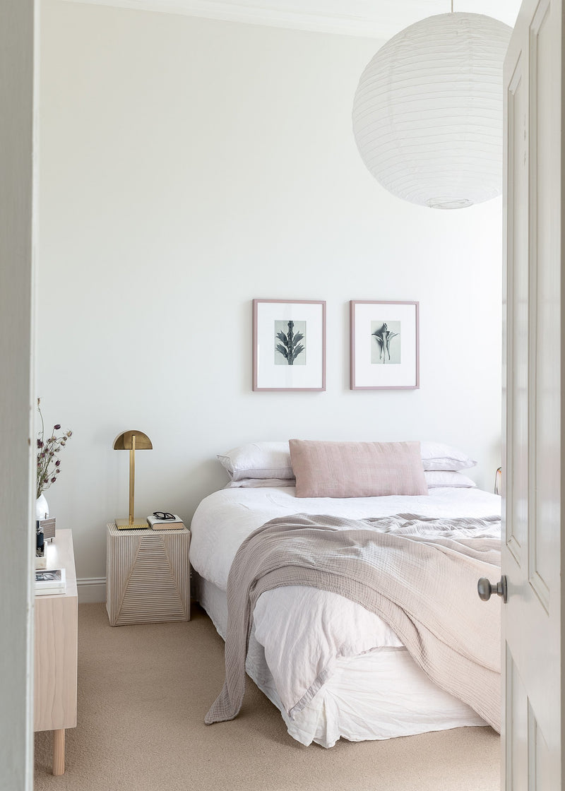 A bedroom with a white bed and a light fixture from Our Spaces - Contemporary New Zealand Interiors brand.