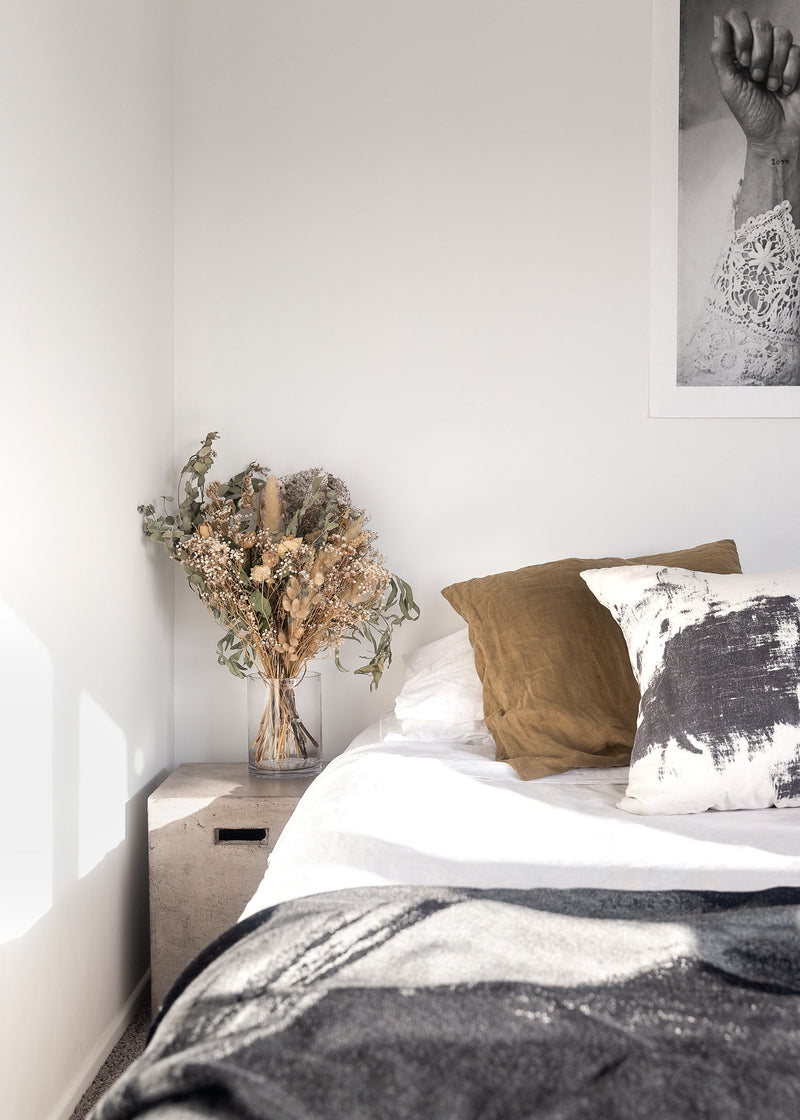 A bedroom with a white bed and a Our Spaces - Contemporary New Zealand Interiors picture on the wall, by Books.