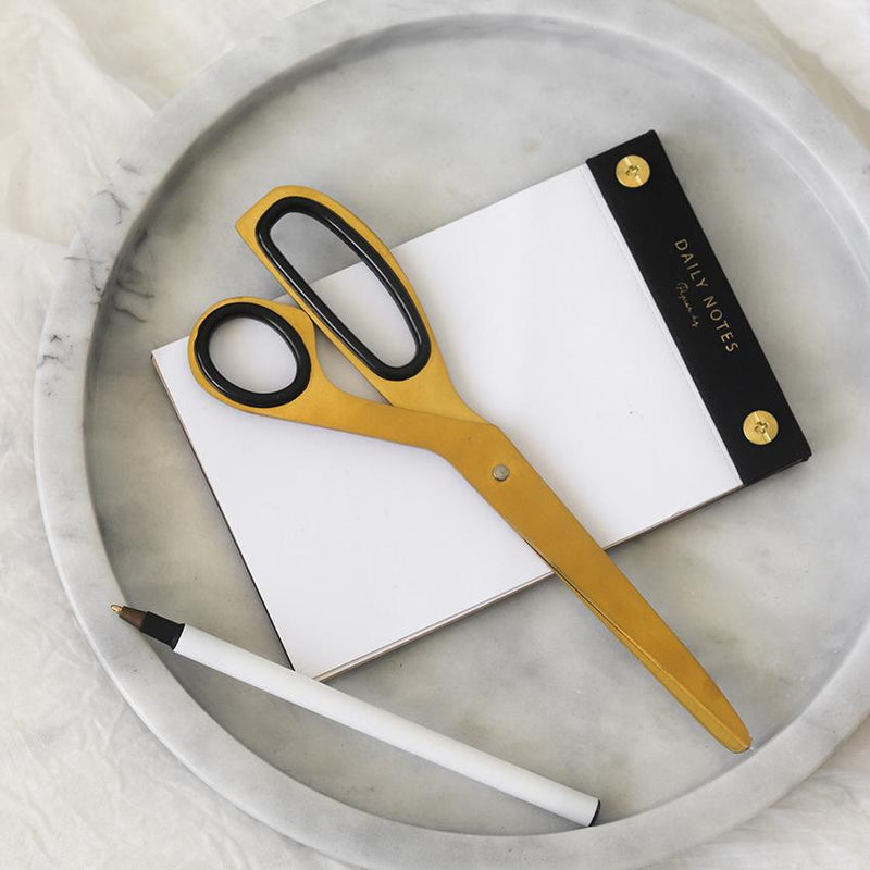 A pair of scissors and a notepad on a Papier HQ marble round tray.