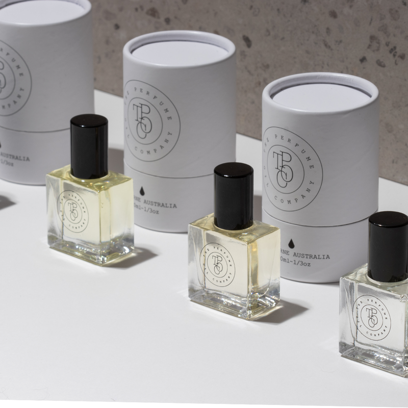 Roll-on perfume oil bottles and white tube cartons on a speckled stone ledge