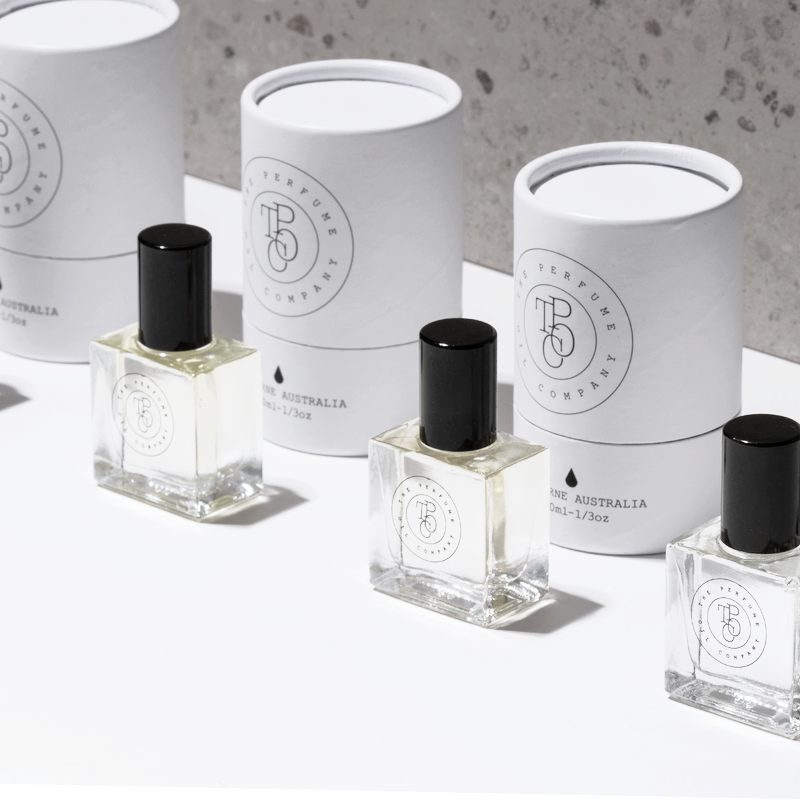 Three perfume oil bottles and gift tubes on a white surface