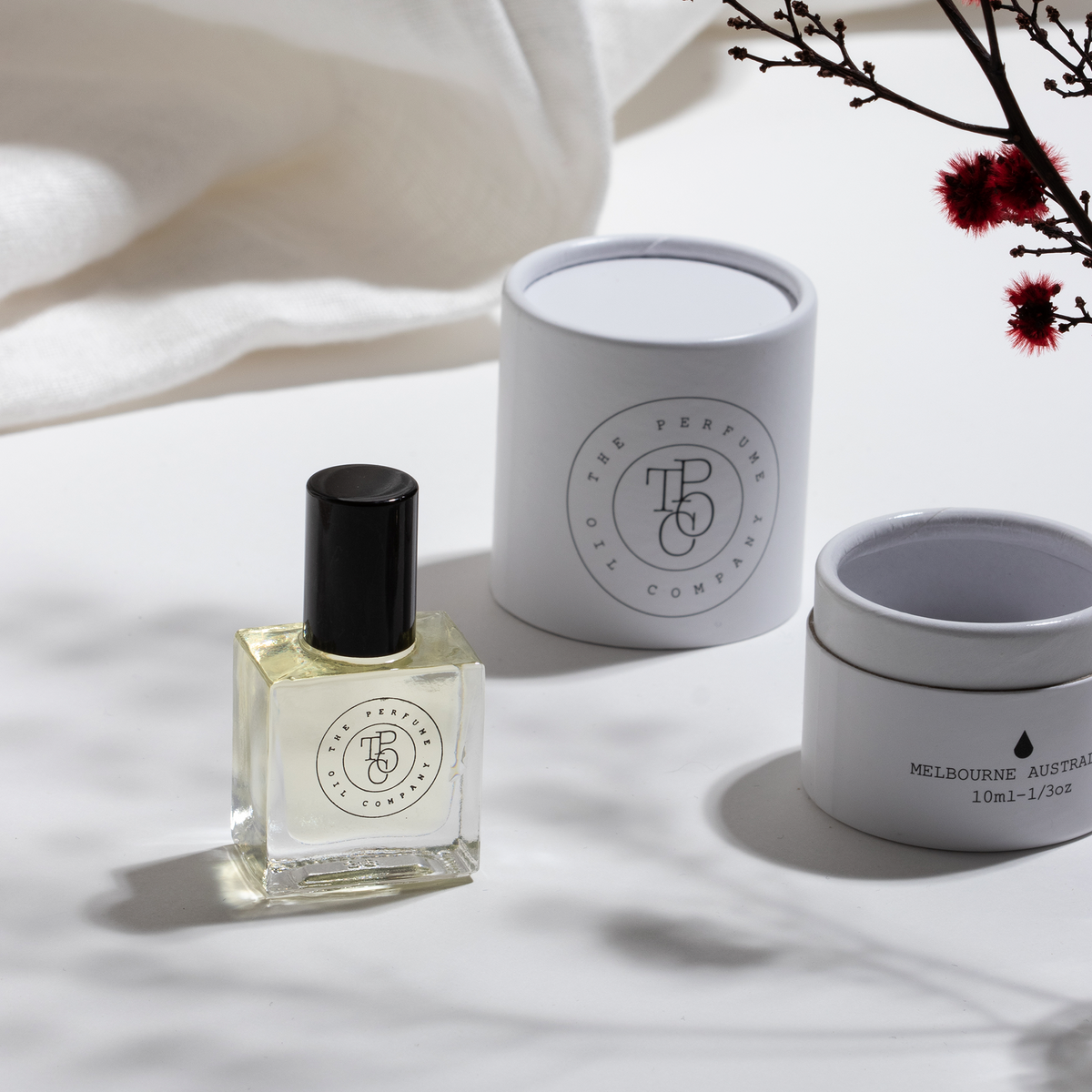 A collection of JETT perfume oils, inspired by Black Orchid from Tom Ford, in a box on a white table. (Brand Name: The Perfume Oil Company)