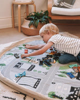 A young boy engaging in imaginative play with a Play Pouch Wow Town Track Interactive city play mat.