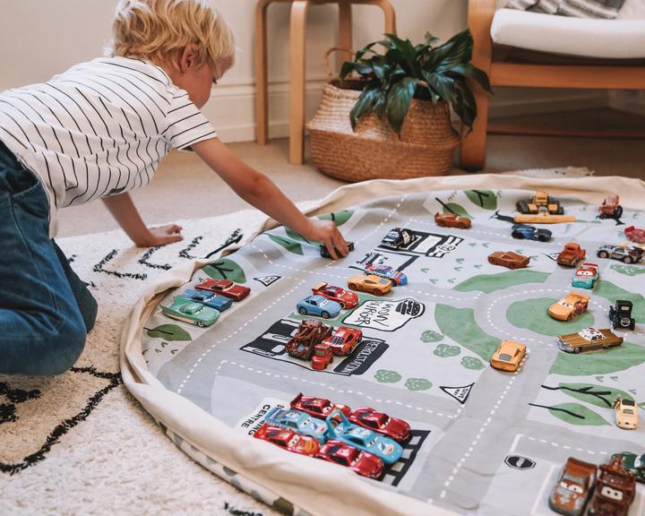 A child engaging in imaginative play on a Play Pouch Wow Town Track Interactive play mat.