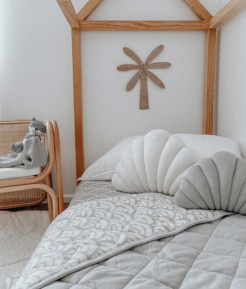 A child's bedroom with a wooden bed and a wooden chair featuring Pure Cotton bedding, as well as the SMALL SHELL CUSHION - MIST / NOUGAT from Bengali Collections.