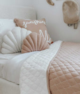 A bed with a LARGE SHELL CUSHION - IVORY decorated with shells from Bengali Collections.