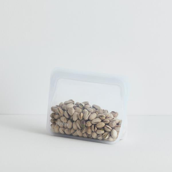 A STAND UP MINI-CLEAR bag filled with peanuts on a white surface.