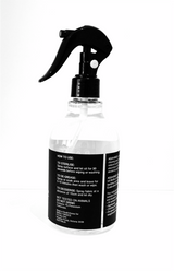 A black bottle with a sprayer on a white surface, containing Barkly Basics Sanitising Surface Spray to kill germs.