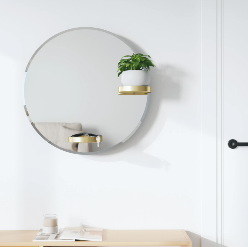Umbra Perch round mirror with brass shelves on a white wall above a console