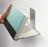 A person using Umbra's Conceal 3 Pack - Silver invisible book shelves to hold an open book.