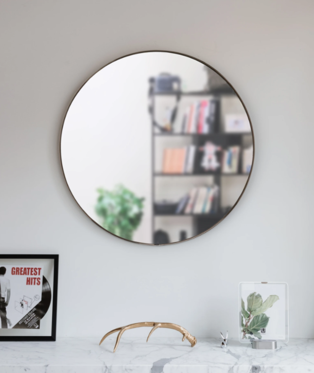 A Hubba Mirror 34 Titanium from the Umbra range on top of a white wall.