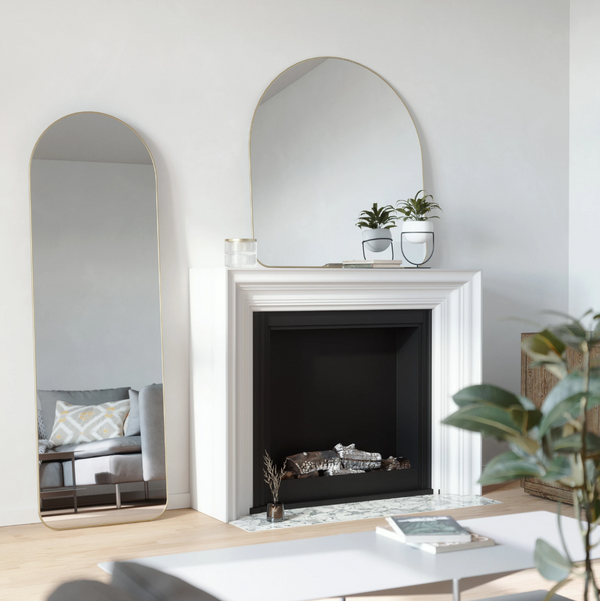 A white living room with Umbra's HUBBA ARCHED LEANING MIRROR - BRASS.