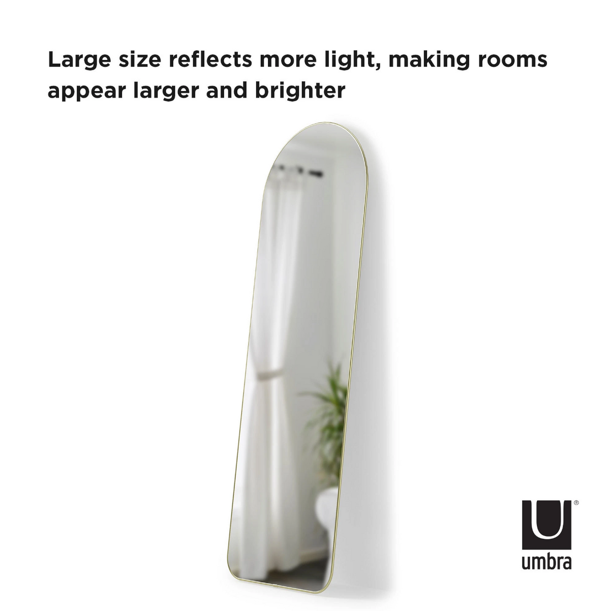 Umbra Hubba arched leaning full length mirror in brass reflecting light in a bright room